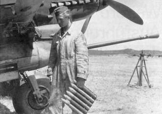 Un mecánico se prepara para alimentar uno de los cañones BK 37 de un Stuka con el peine de seis proyectiles con cabeza de wolframio que lleva en la mano